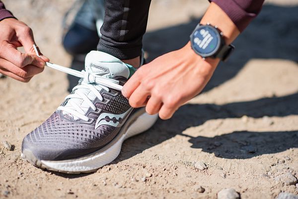 Un corredor se ata el zapato y pone su reloj antes de correr