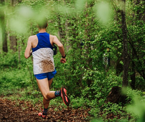 Un corredor con la espalda salpicada de barro corre por el bosque