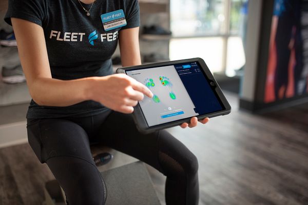 Un proveedor de Fleet Feet señala un escaneo de un pie en un ipad